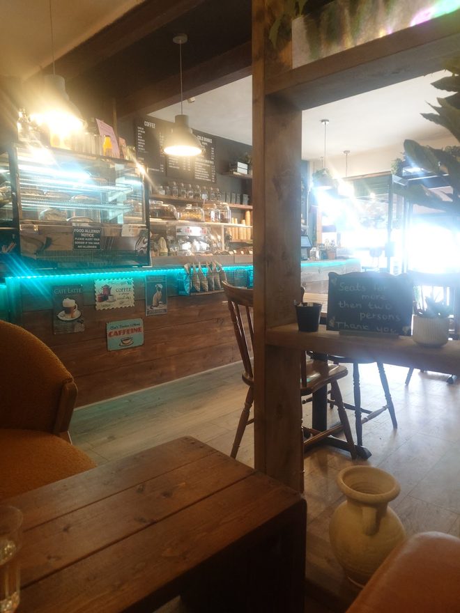 The lit counter and display cabinet seen past a timber post, with a table in the foreground