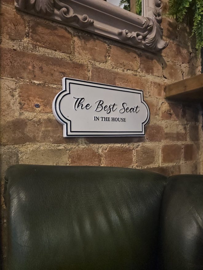 A green leather sofa against exposed brick, crop the framed plaque and its burned-in lettering out of the top of frame