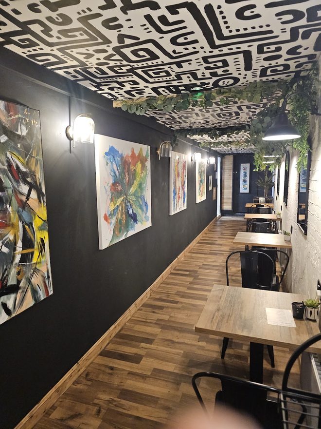 The wall of colourful framed prints above a row of tables
