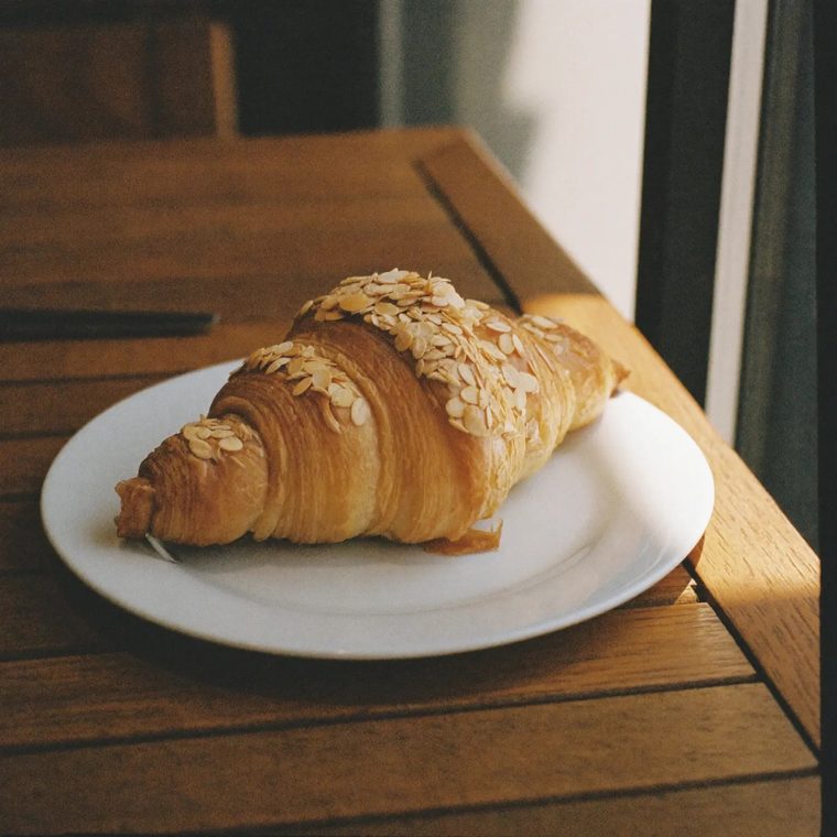 An almond croissant on a small white plate