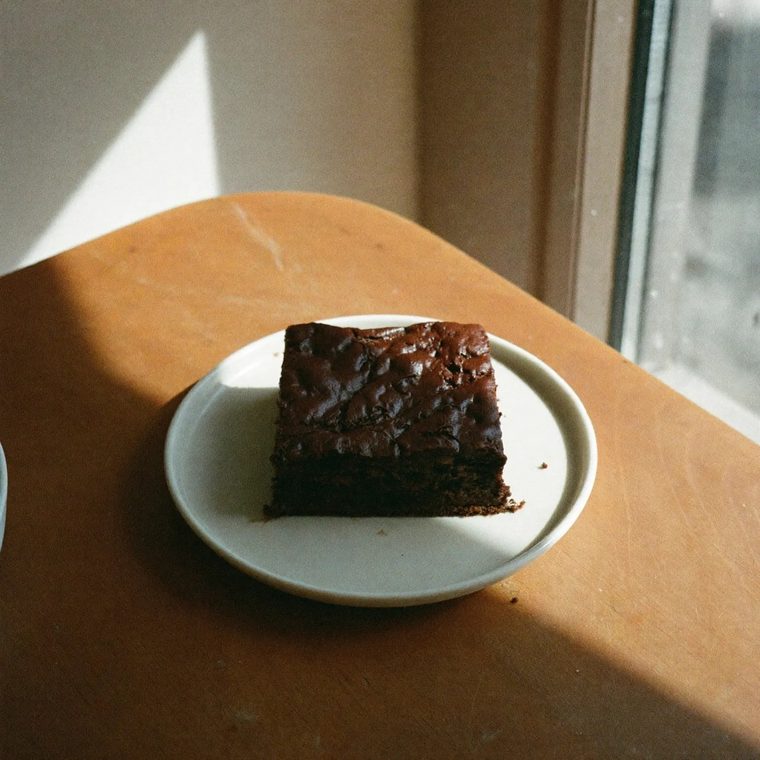 A chocolate brownie square on a small plate